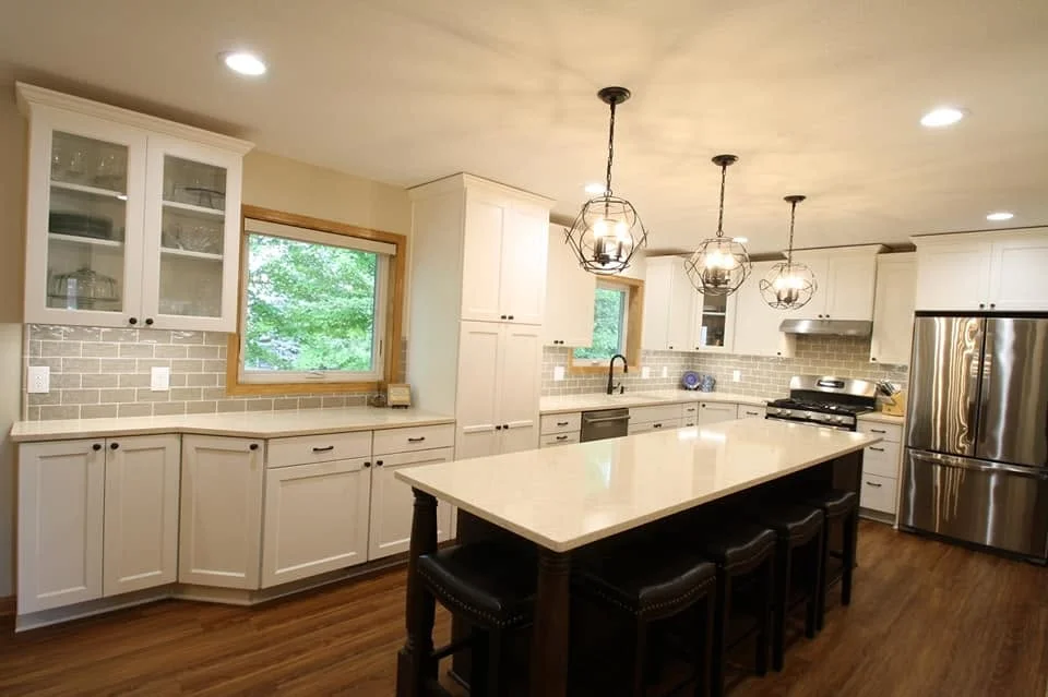 Modern kitchen with white cabinets, black island, subway tile backsplash, and stainless steel appliances