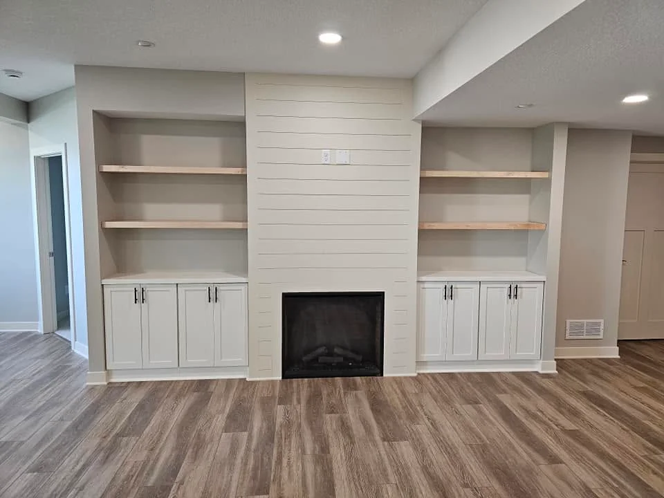 Custom white built-in cabinetry with shelving and electric fireplace in finished basement