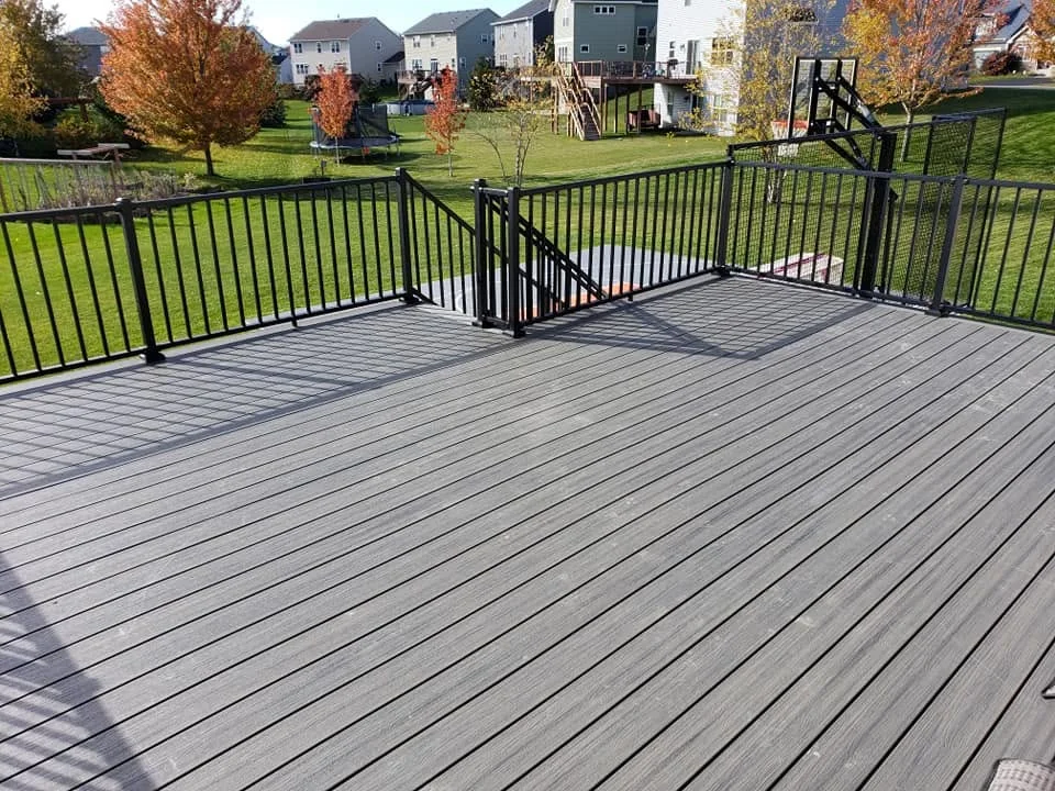 Large composite deck with black aluminum railings and stairs in residential setting