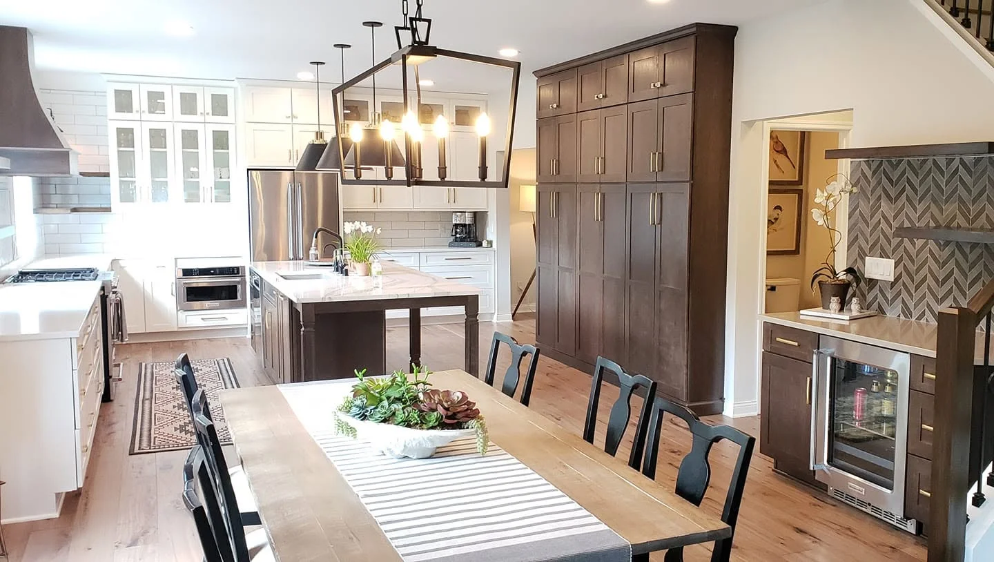 Modern kitchen with white and dark wood cabinets, marble island, and dining area